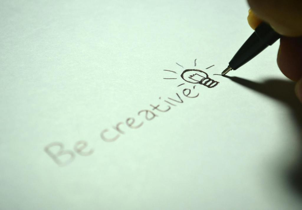 A hand holding a pen writes 'Be creative' on a piece of paper, accompanied by a lightbulb illustration.